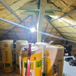 Rafał Muller LOGOS - Ocieplenie poddasza wełną mineralną Isover Super-Mata, widoczne profile metalowe i narzędzia. Prace wykończeniowe na poddaszu, izolacja termiczna dachu.