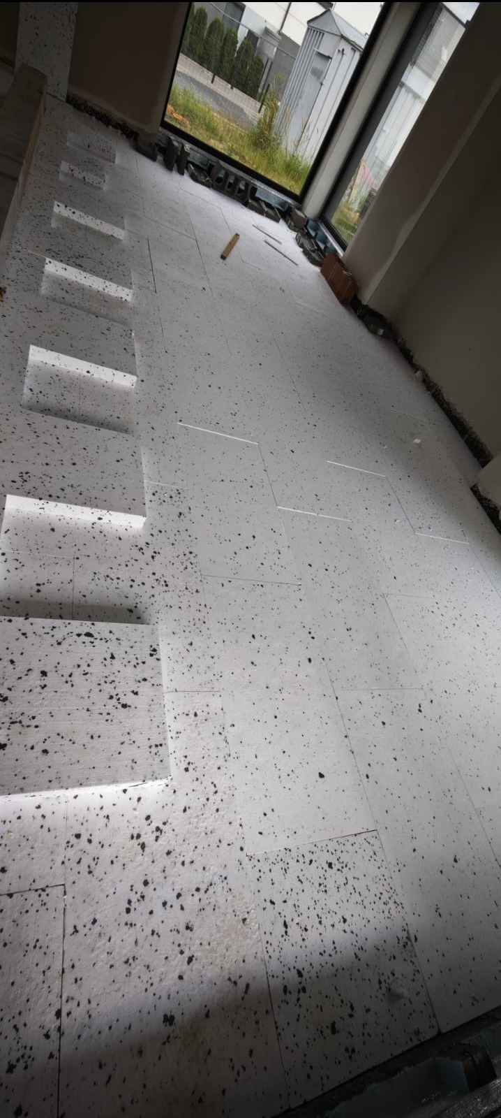 Dom jednorodzinny. Układanie styropianu na podłodze przed posadzką.