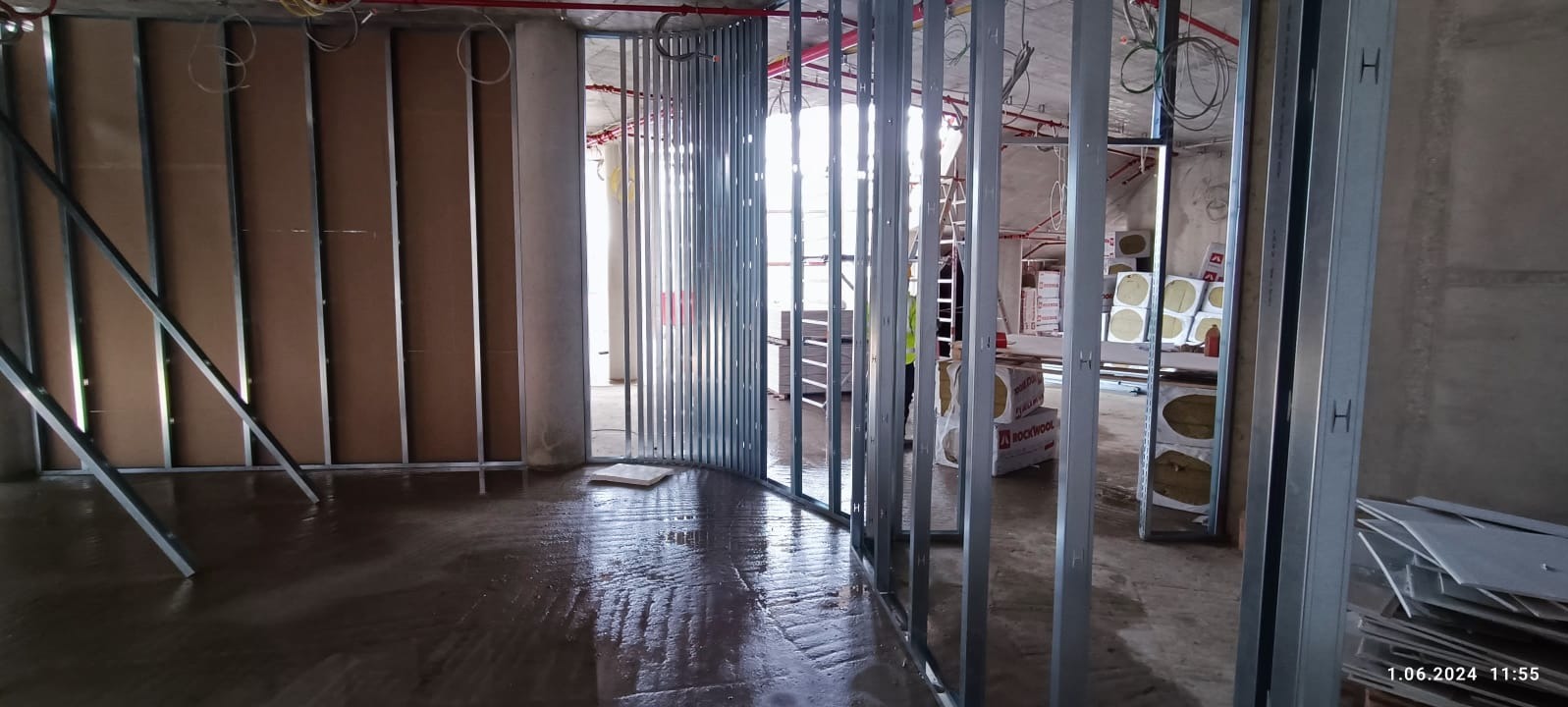 Wnętrze w trakcie prac wykończeniowych: metalowe profile ścian działowych, płyty karton-gips, izolacja Rockwool. Widoczne instalacje pod sufitem.