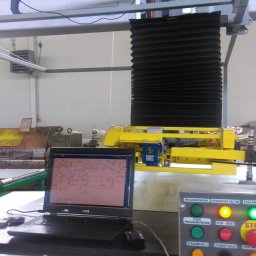 ZUEA BIAŁOWSKI - Panel sterowania maszyny przemysłowej z podłączonym laptopem Dell, na ekranie schemat elektryczny. Widoczne przyciski i diody sygnalizacyjne.