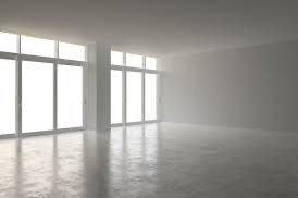 Jasne, puste wnętrze z dużymi oknami i betonową podłogą. Minimalistyczny design, surowe wykończenie, widoczne refleksy światła na podłodze. Przestrzeń gotowa do aranżacji.