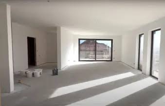 Jasne, przestronne wnętrze po malowaniu, z widocznymi śladami farby na podłodze i wiaderkami farby w rogu, sugerujące świeżo zakończone prace wykończeniowe.