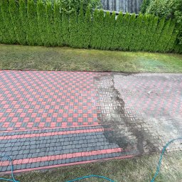 Bartłomiej Wojda - Częściowo umyta kostka brukowa w odcieniach czerwieni i szarości, z widocznym wężem ogrodowym i zielonym żywopłotem w tle. Widoczny efekt czyszczenia.