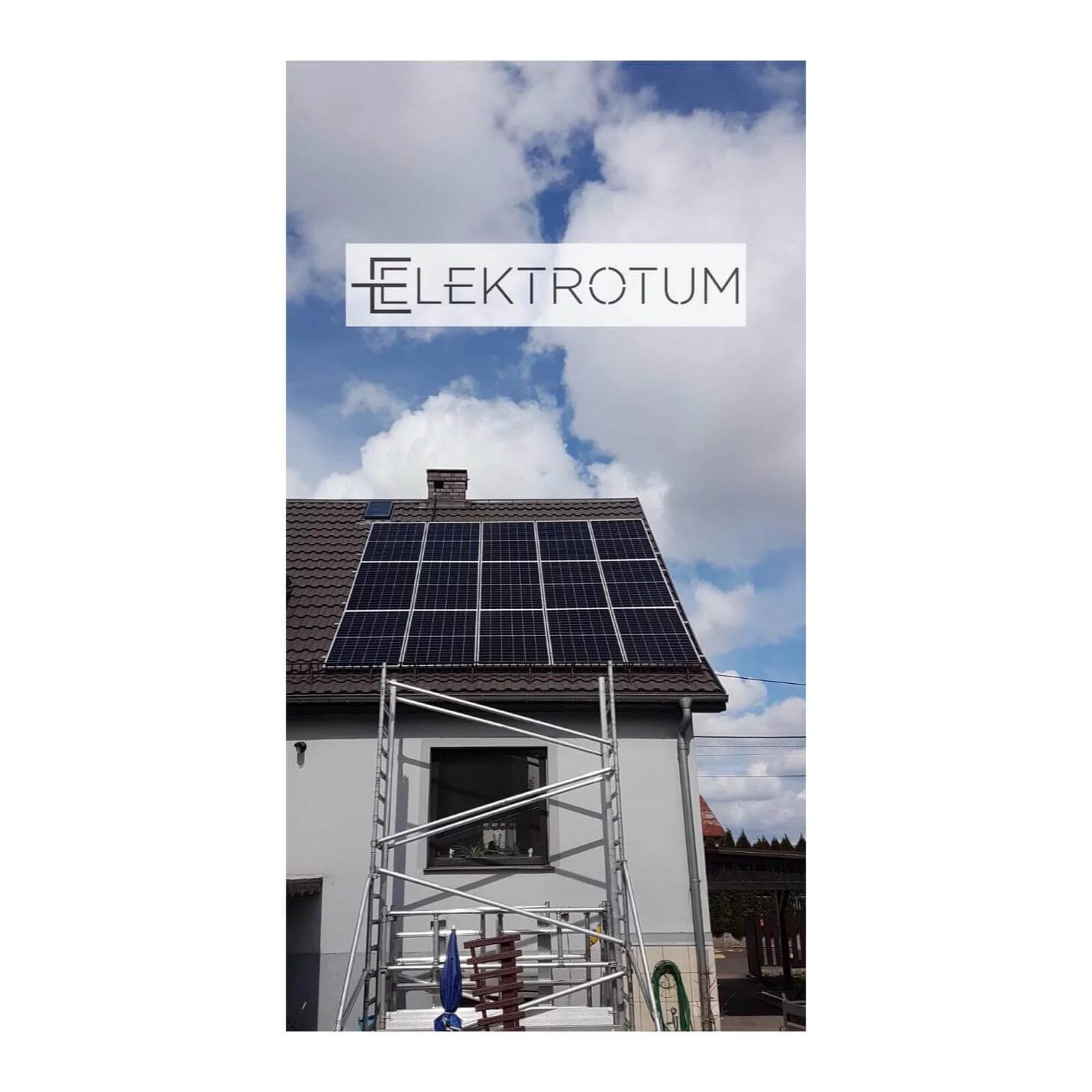Dom z panelami fotowoltaicznymi na dachu, widoczne rusztowanie i logo firmy ELEKTROTUM na tle błękitnego nieba z chmurami. Instalacja w trakcie montażu.