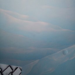 Aleksander Burkenia SPOKOBUD - Niebieska ściana z efektem chmur i fragmentem dekoracyjnej struktury w rogu. Delikatne przejścia kolorów tworzą iluzję przestrzeni.