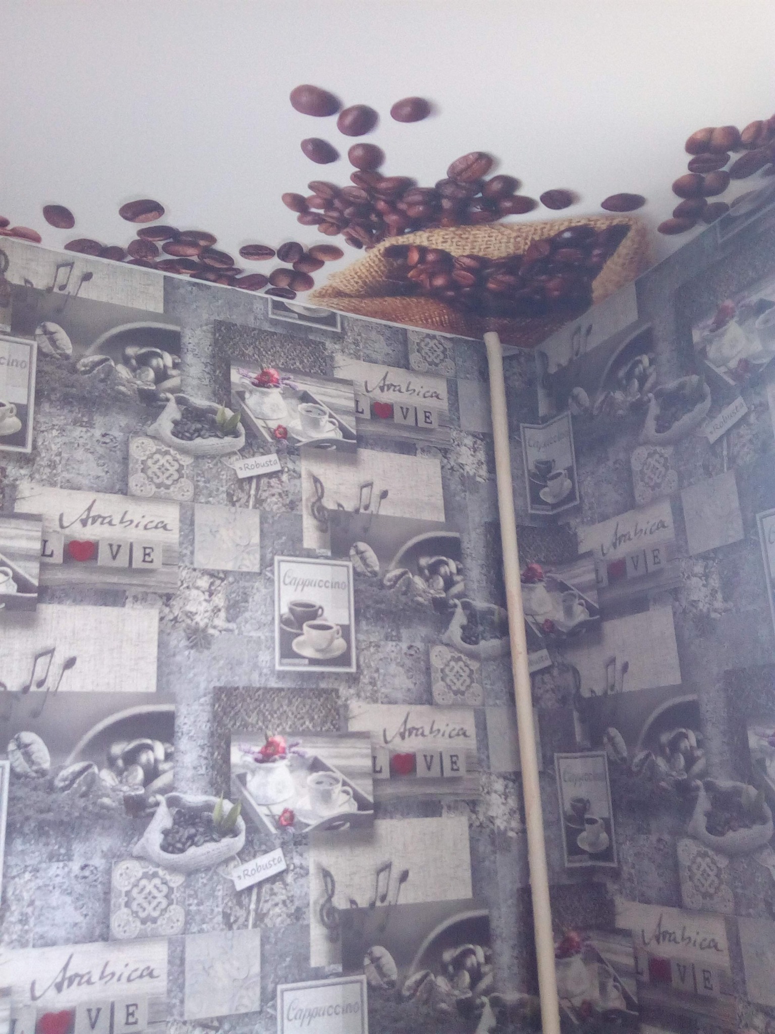 Kawiarniany motyw na tapecie z motywem kawy i ziaren, dekoracja sufitu z motywem kawy, pionowa listwa na tle wzorzystej ściany.