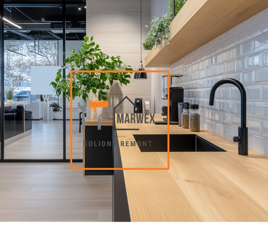 Nowoczesna kuchnia z drewnianym blatem, czarną armaturą i białymi płytkami typu metro. Rośliny doniczkowe dodają świeżości. Widoczny fragment biura za szklaną ścianą.