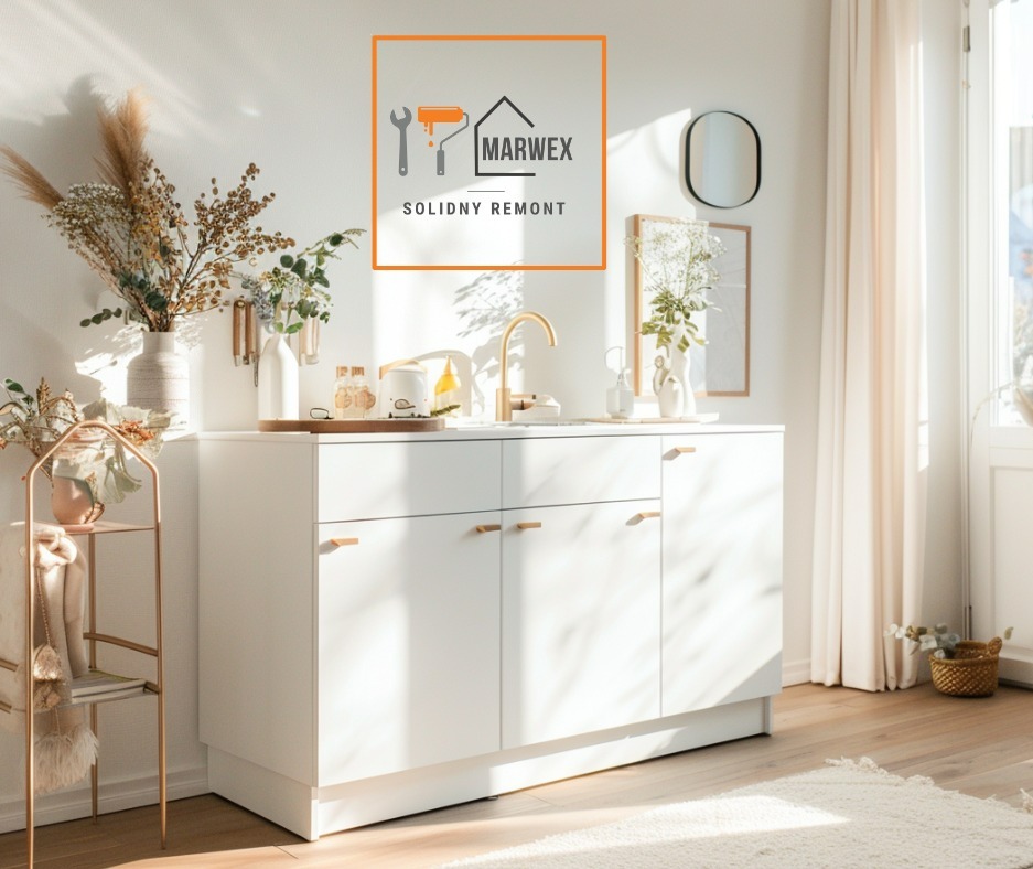 Biała szafka łazienkowa z złotą armaturą i dekoracjami w jasnym wnętrzu, logo firmy remontowej w rogu. Minimalistyczny design, naturalne światło.