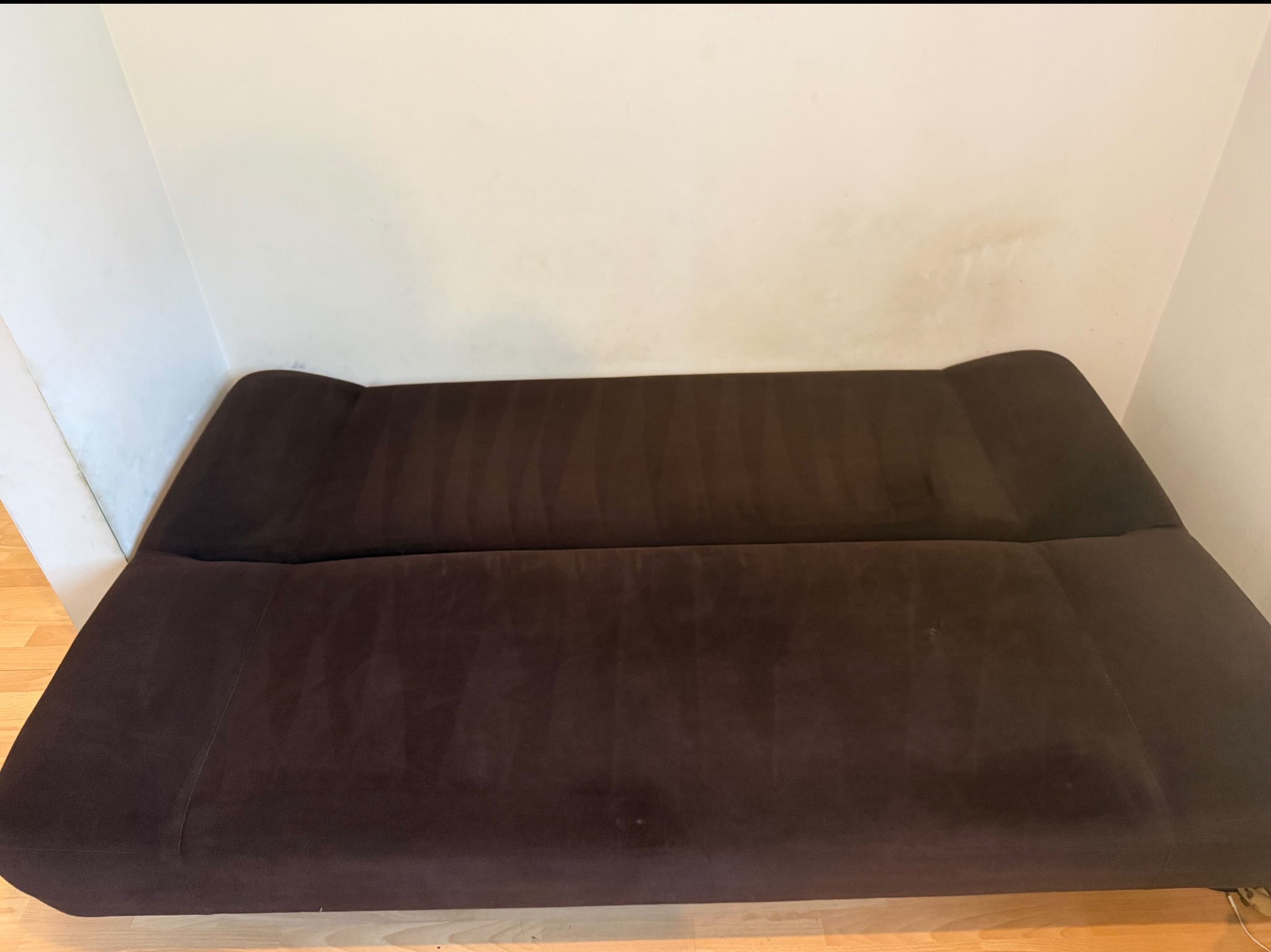 Ciemnobrązowa kanapa po praniu tapicerki, widoczne ślady czyszczenia na materiale. Ujęcie z góry, ukazujące efekt odświeżenia tkaniny.