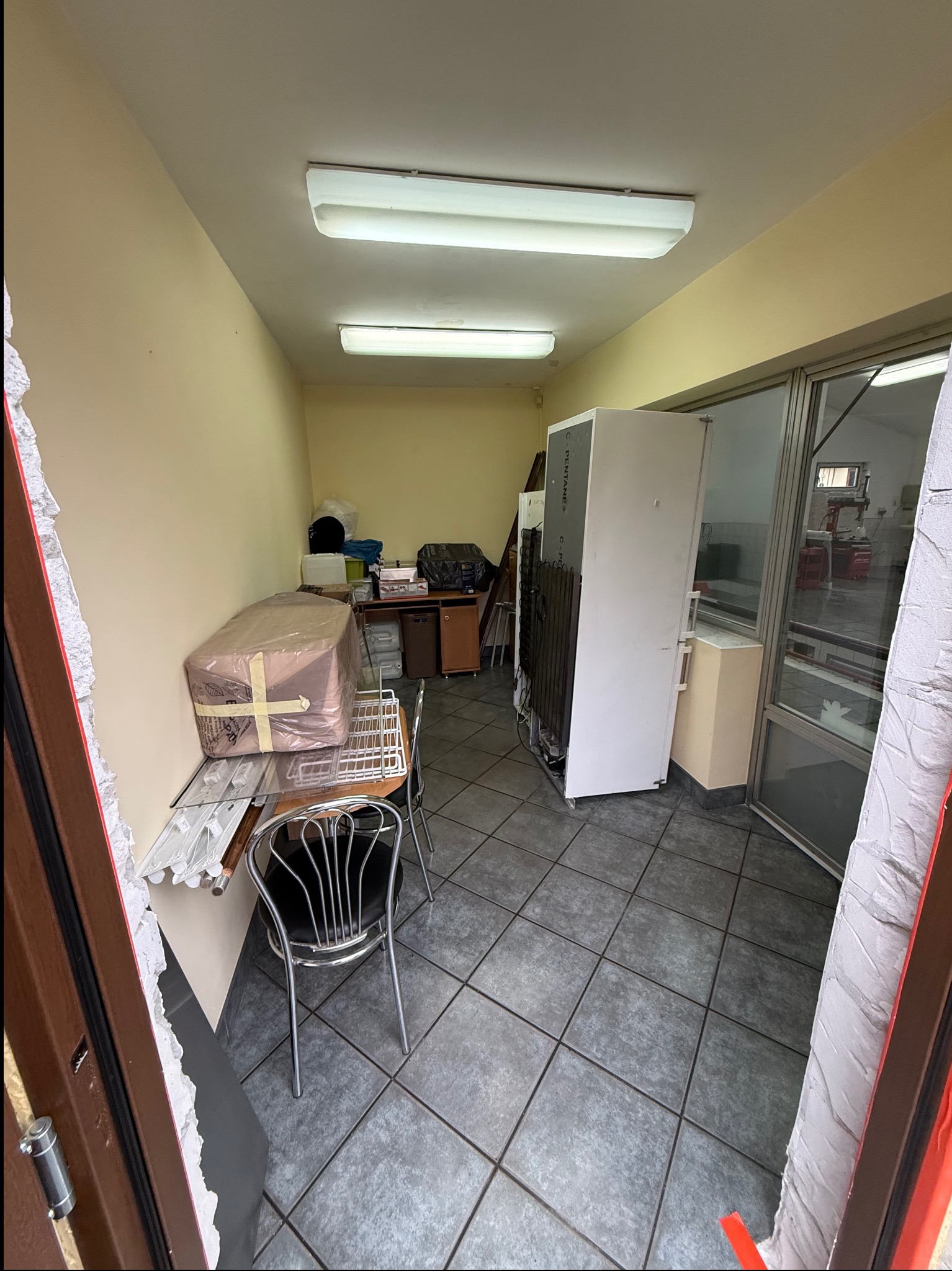 Wnętrze pomieszczenia w trakcie opróżniania: meble, sprzęty i kartony przygotowane do wyniesienia. Widoczne ślady po remoncie przy futrynie drzwi.