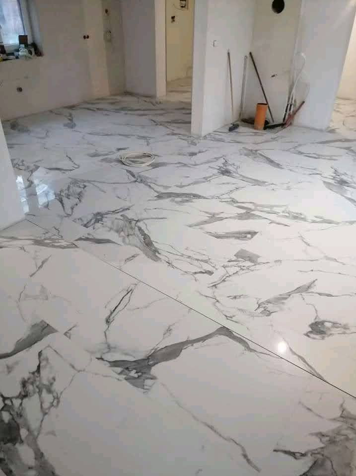 Biała podłoga z marmurowym wzorem w wyremontowanym pokoju. Widoczne narzędzia i akcesoria malarskie przy ścianie. Nowoczesne wykończenie wnętrza.