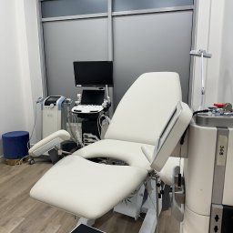 MW Medic - Medycyna Estetyczna Warszawa - Jasne wnętrze gabinetu z białym fotelem zabiegowym, aparaturą medyczną i schodkiem. Minimalistyczny wystrój, nowoczesne oświetlenie, drewniana podłoga.