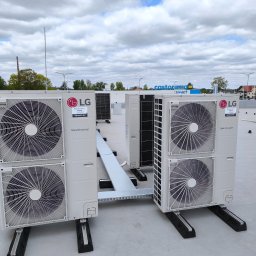 EcoGlobal Arkadiusz Juszczak - Dwa zestawy klimatyzatorów LG Smart Inverter na dachu budynku, połączone kanałem. W tle widoczny budynek Castorama Smart i pochmurne niebo.