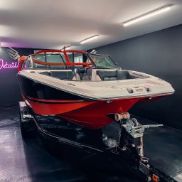 COLOR DETAIL SPÓŁKA Z OGRANICZONĄ ODPOWIEDZIALNOŚCIĄ - Lśniąca, czerwono-biała łódź motorowa na czarnej przyczepie w sterylnym garażu z neonowym napisem 'Detail'. Perfekcyjny połysk i dbałość o detale.