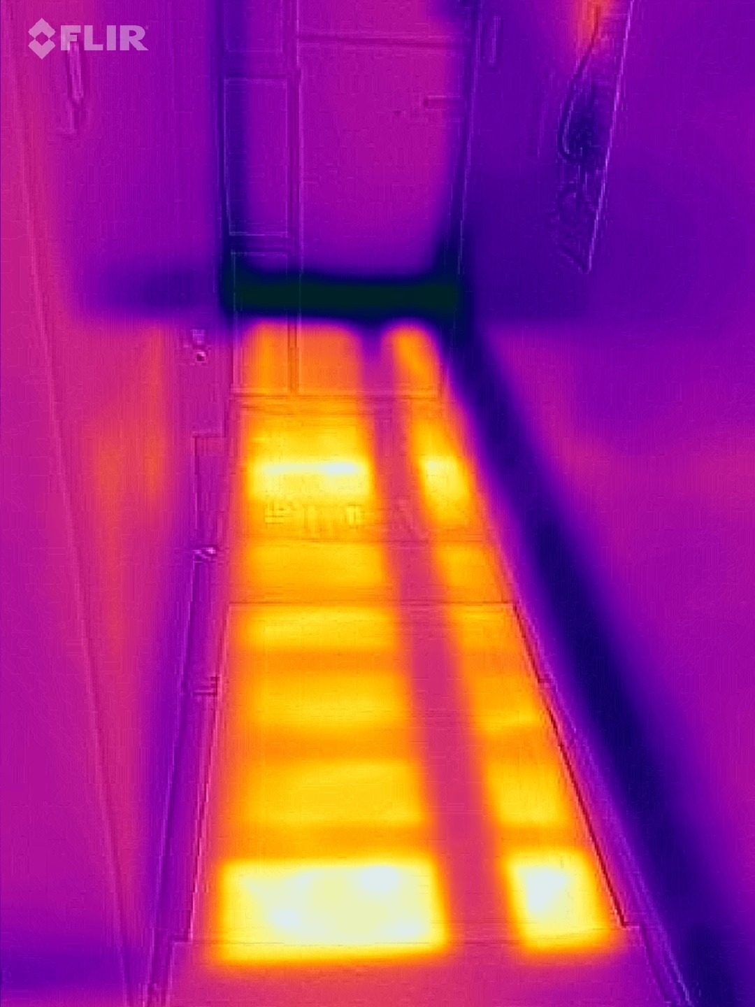 Termowizja podłogowa: ciepłe strefy na schodach w fioletowo-żółtej kolorystyce, ukazujące efektywność ogrzewania. Widoczne detale instalacji pod podłogą.