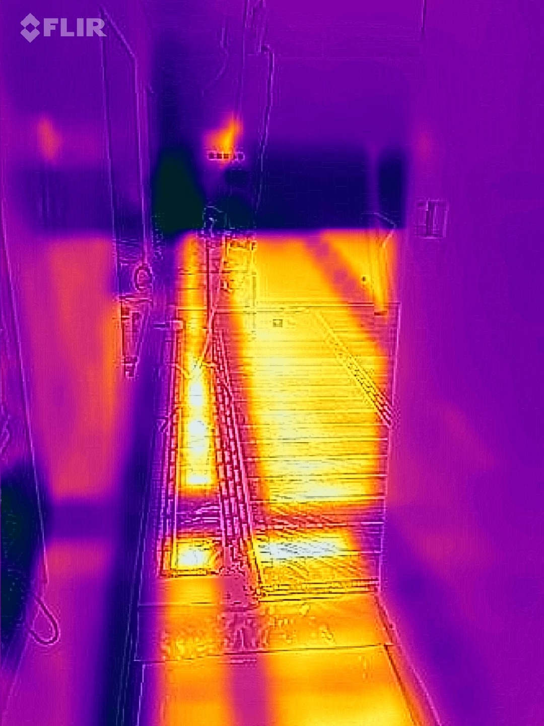 Termowizja podłogowa: ciepłe rury grzewcze pod panelami, widoczne na obrazie termograficznym w odcieniach fioletu i żółci. Analiza rozkładu temperatury.