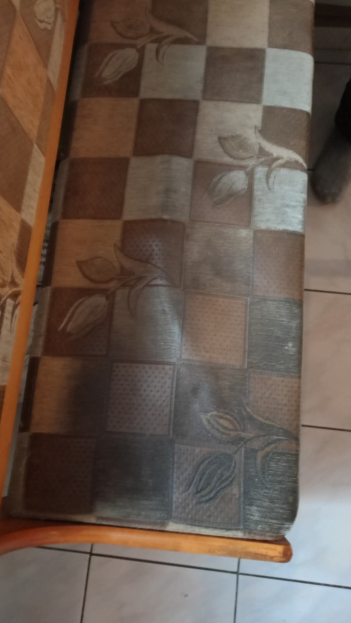 Szczegółowe ujęcie wzorzystego siedziska krzesła z motywem kwiatowym i kratką, ukazujące potencjalne zabrudzenia i potrzebę odświeżenia tapicerki.