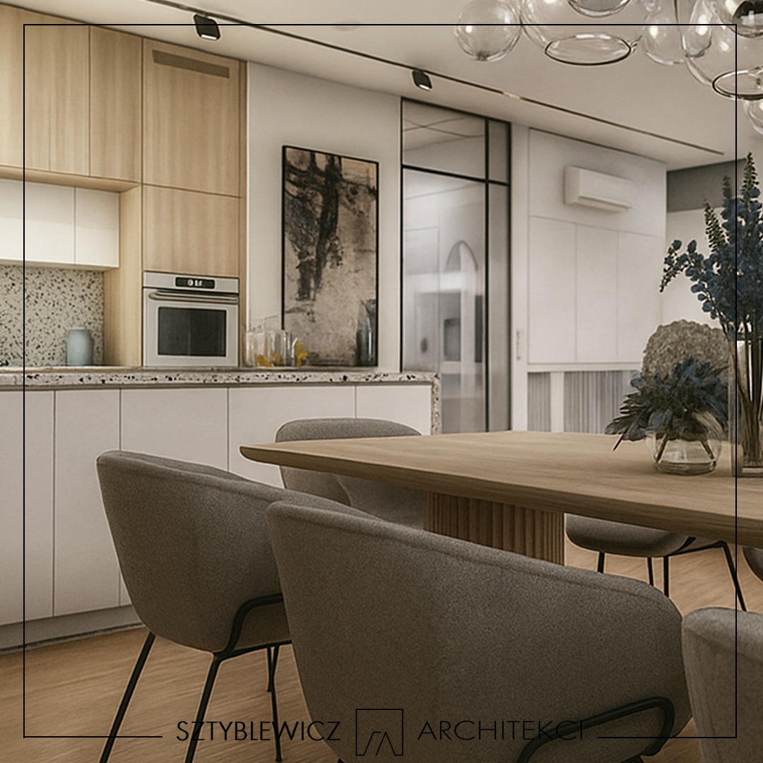 Jasna kuchnia z drewnianymi szafkami i blatem z lastryko, połączona z jadalnią. Nad stołem dekoracyjna lampa z szklanych kul. Na ścianie abstrakcyjny obraz.