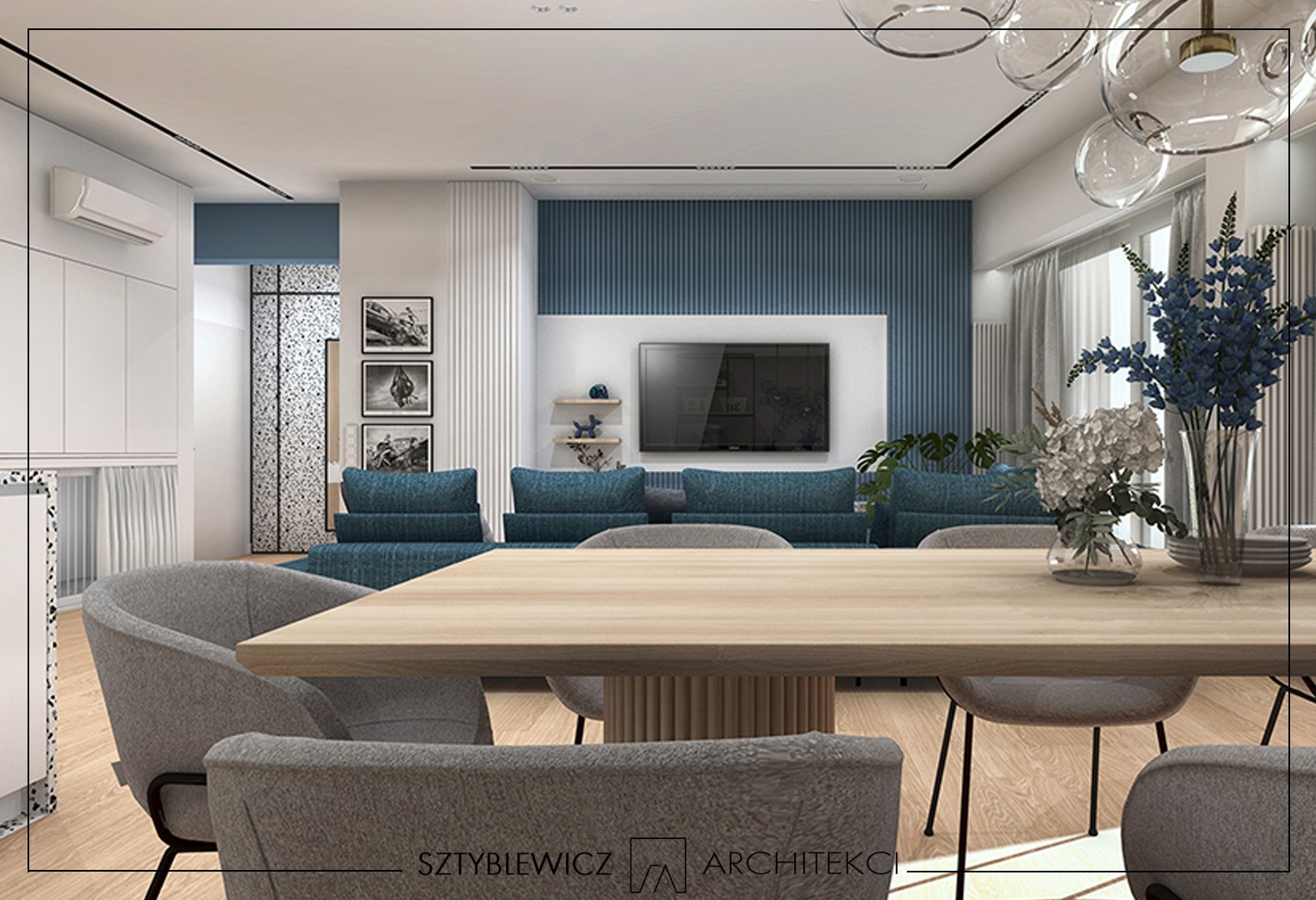 Nowoczesna aranżacja salonu z drewnianym stołem, szarymi krzesłami i niebieską sofą. W tle ściana z telewizorem i dekoracjami. Całość w jasnych, stonowanych barwach.