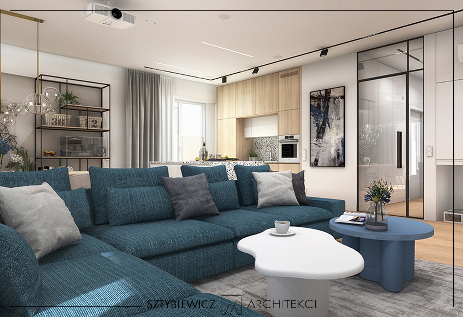 Wnętrze salonu z aneksem kuchennym: turkusowa sofa narożna, biały stolik kawowy, drewniane szafki kuchenne, oświetlenie punktowe i projektor na suficie.