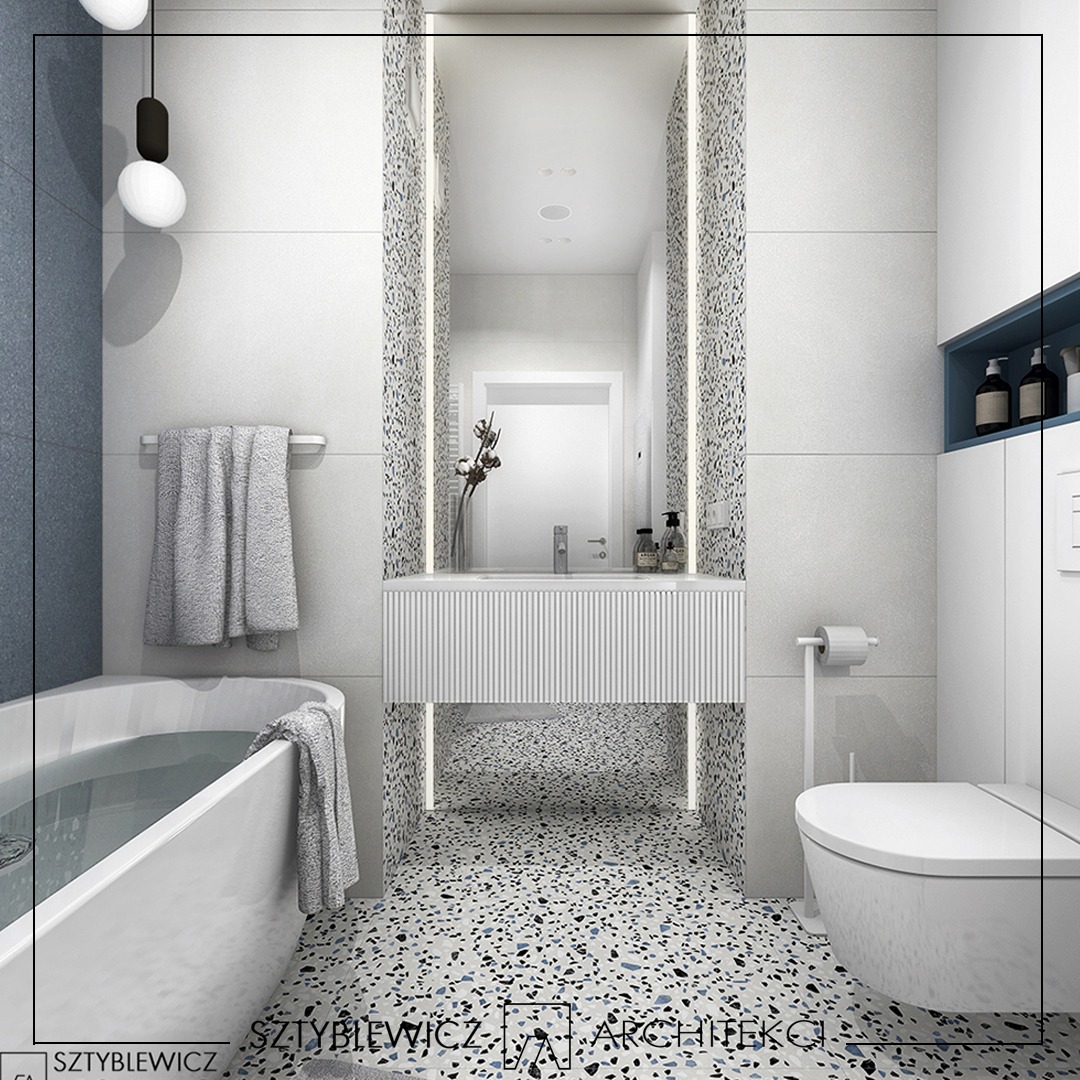 Nowoczesna łazienka z wanną, umywalką na podeście z ryflowanym frontem i toaletą. Uwagę przykuwa podłoga i ściany wykończone lastryko w odcieniach bieli i błękitu.