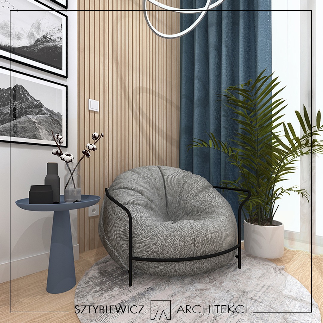 Wizualizacja wnętrza: szary fotel typu pufa z czarną ramą, okrągły stolik z dekoracjami, drewniana ściana z lameli i zasłona w odcieniach niebieskiego.