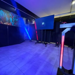 EVENTIVITY GROUP PAULINA TRYTKO - Nowoczesna fotobudka z ekranem, oświetleniem LED (czerwone i niebieskie) i interaktywnymi przyciskami, ustawiona w pomieszczeniu z dekoracyjną tapetą i profesjonalnym nagłośnieniem.