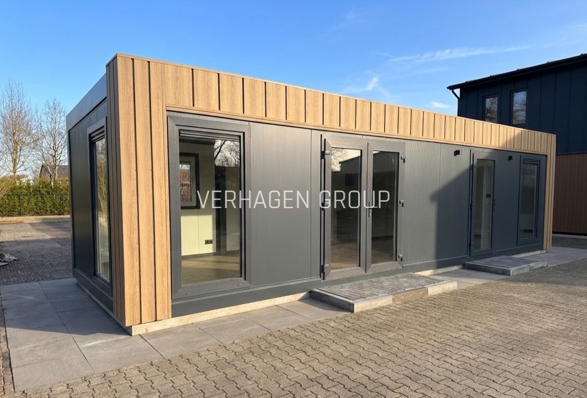 Nowoczesny, parterowy dom modułowy z szarymi ścianami i drewnianą okładziną, widoczny z zewnątrz w słoneczny dzień. Minimalistyczny design z dużymi oknami.