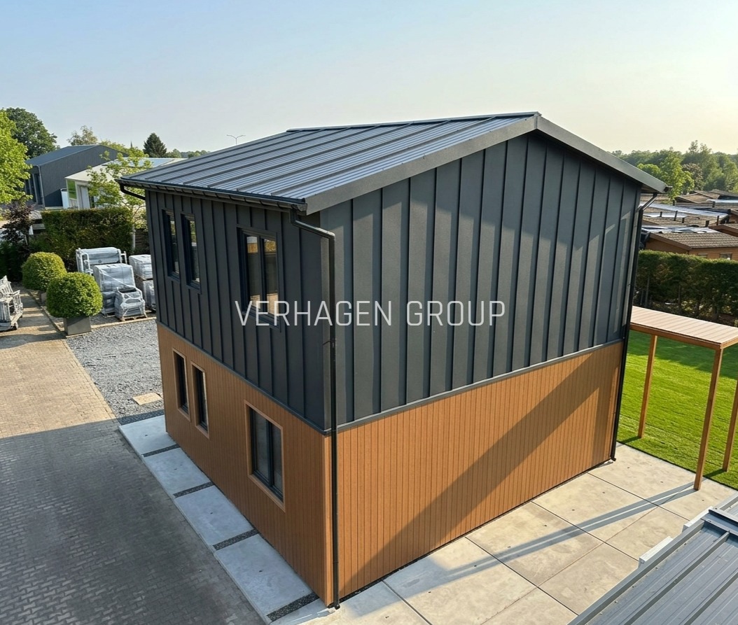 Dwukondygnacyjny dom modułowy z szarej blachy falistej i brązowych paneli, widok z góry, z logo firmy na elewacji. Nowoczesna architektura.