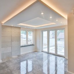 PORTAL Maciej Hyżowiecki - Jasne wnętrze z szarą, marmurkową podłogą, dekoracyjną ścianą z paneli i podwieszanym sufitem z oświetleniem LED. Nowoczesny design, duże okna.