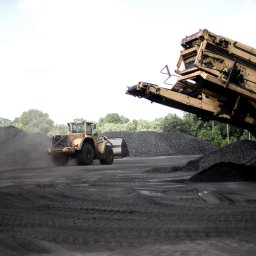 Agencja Marketingowa APOV - Żółta ładowarka Volvo i przesiewacz Extec na tle hałdy w Mińsku Mazowieckim. Sprzęt budowlany w trakcie pracy, widoczne ślady opon i pył.