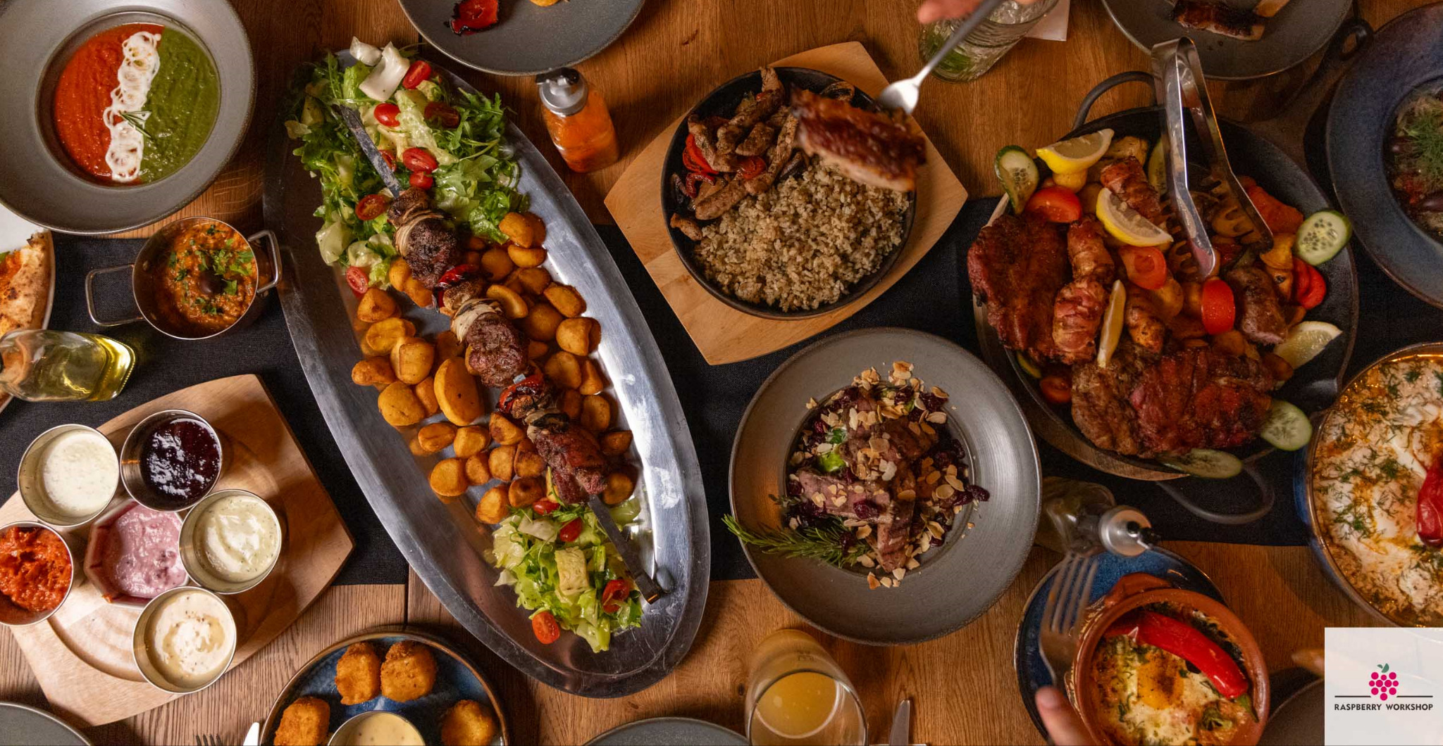 Bogato zastawiony stół z różnorodnymi daniami mięsnymi, sałatkami i sosami, tworzący apetyczną kompozycję kulinarną z bliska, idealną na imprezę firmową.