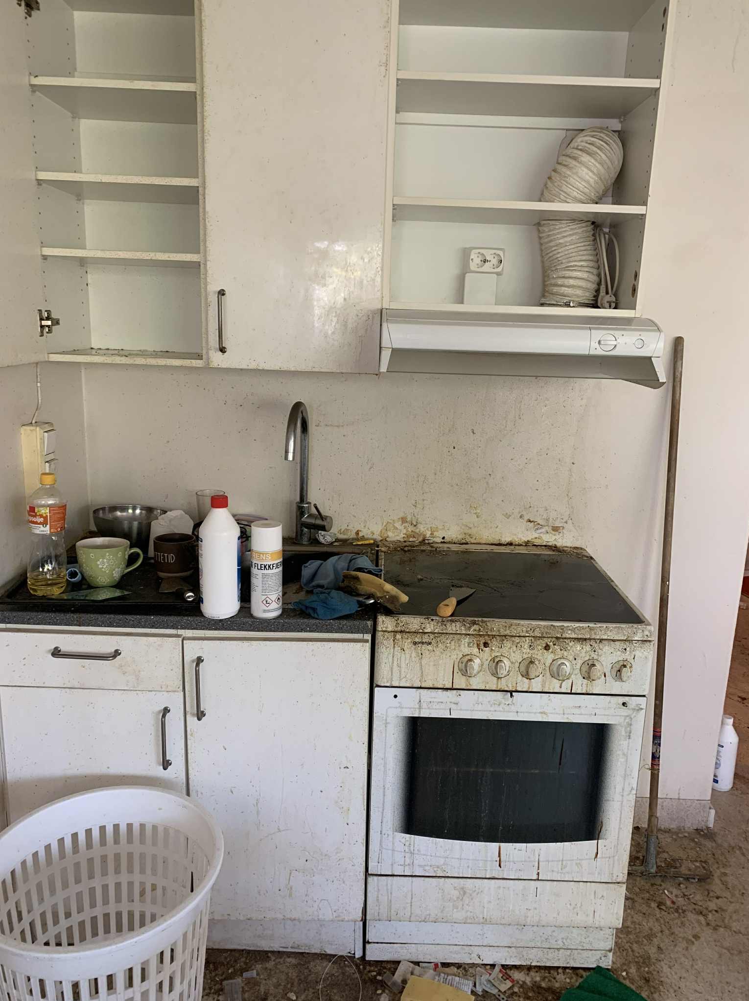 Zaniedbana kuchnia z brudnym piekarnikiem, szafkami i blatem. Widoczne plamy, resztki jedzenia i ogólny brak czystości. Potrzebne gruntowne sprzątanie.