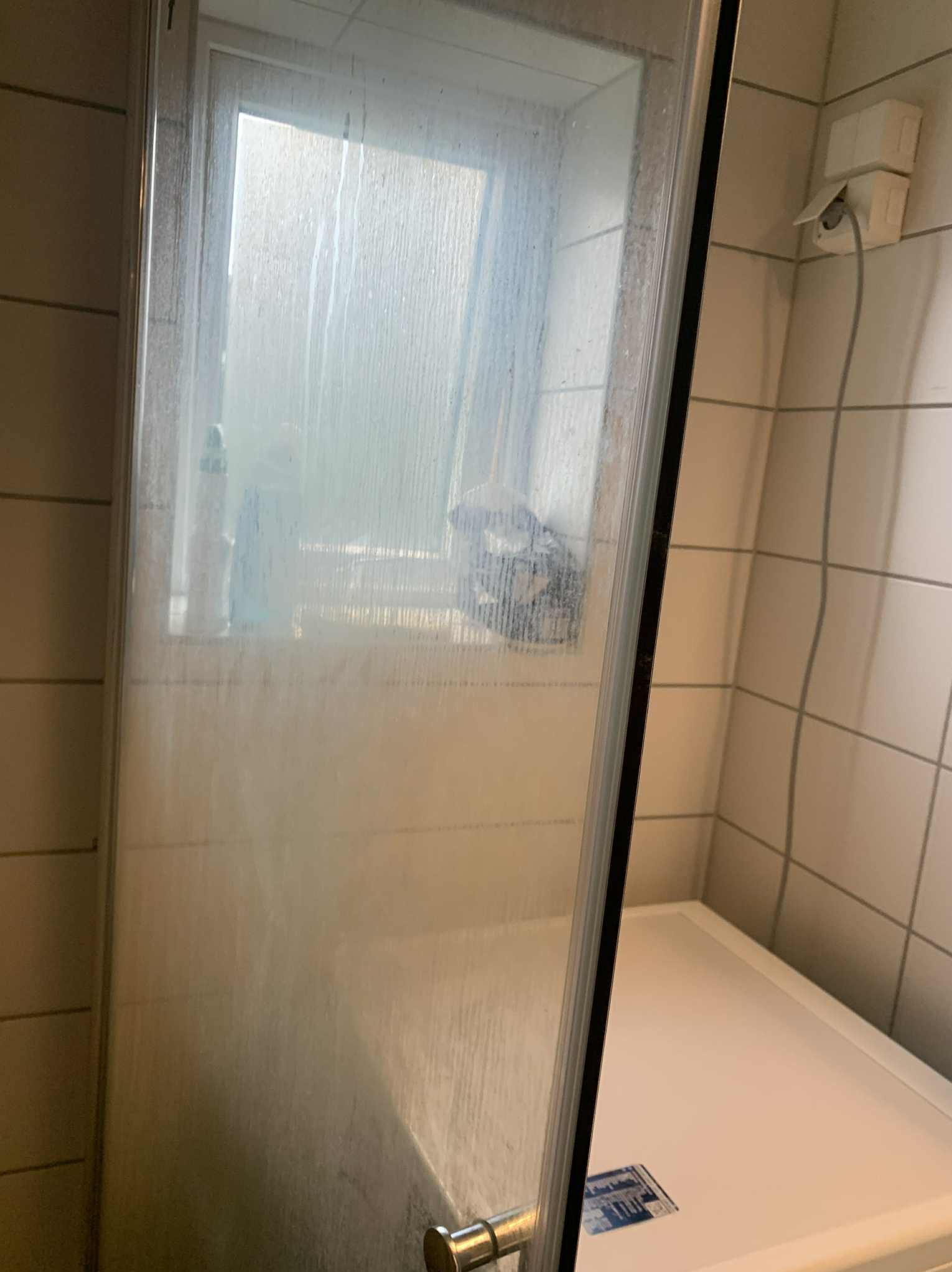 Zapuszczona kabina prysznicowa przed czyszczeniem w łazience w Radomiu. Widoczne zacieki i osad na szklanej powierzchni.