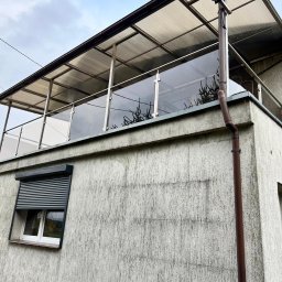 Air-Send - Szklana balustrada balkonowa z zadaszeniem, widok z dołu, z rynną i oknem z roletą. Nowoczesny design z elementami metalowymi.