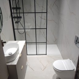 entreprise - Nowoczesna łazienka z kabiną prysznicową typu walk-in z czarnymi profilami, umywalką nablatową i podwieszaną toaletą. Płytki imitujące marmur na ścianach i podłodze.