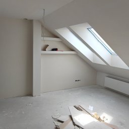 entreprise - Jasne poddasze po remoncie: skośne okno dachowe, świeżo pomalowane ściany w odcieniach bieli, grzejnik, widoczne ślady po gniazdkach elektrycznych, surowe wykończenie podłogi.