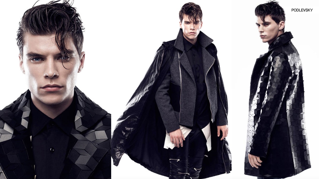 Męski model prezentuje awangardowy płaszcz z geometrycznym wzorem, w stylizacji z czarną koszulą i skórzanymi spodniami, na białym tle. Ujęcie z bliska i pełnej sylwetki.