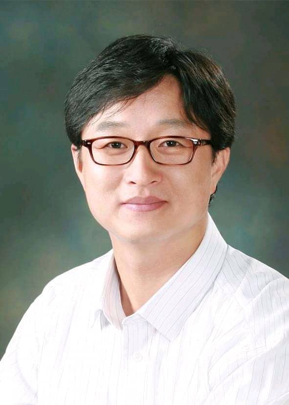 Portret uśmiechniętego mężczyzny w okularach i białej koszuli na rozmytym tle. Profesjonalny wizerunek doradcy finansowego lub kredytowego.