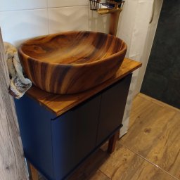 GLAZURKARZ Mateusz Moskwa - Drewniana misa umywalkowa na szafce w łazience z drewnianą podłogą. Nowoczesna armatura i akcesoria łazienkowe. Ujęcie z bliska, detale wykończenia.