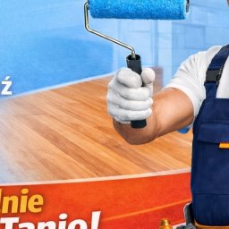 Edyta Kowalska Roomcajs - Malarz z wałkiem w rękawicy, w niebieskim kombinezonie, na tle pomalowanej ściany i drewnianej podłogi. Widoczny fragment reklamy z hasłem.