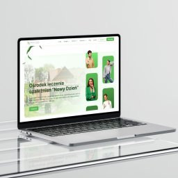 Jedenastka Studio - Laptop prezentuje stronę internetową ośrodka leczenia uzależnień 'Nowy Dzień' z zieloną kolorystyką i zdjęciami personelu. Widoczny nagłówek, menu i fragment treści strony.