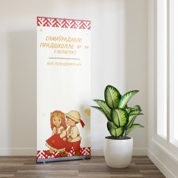 Jedenastka Studio - Roll-up z ilustracją dzieci w strojach ludowych i napisem w języku białoruskim, stojący w jasnym pomieszczeniu obok rośliny doniczkowej.