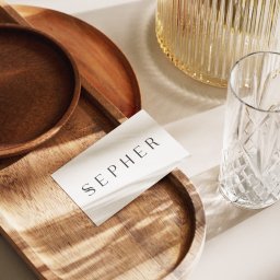 Jedenastka Studio - Elegancka wizytówka SEPHER na drewnianej tacy, obok szklanki z kryształowym wzorem i wazonem w prążki, w ciepłym świetle słonecznym tworzącym cienie.