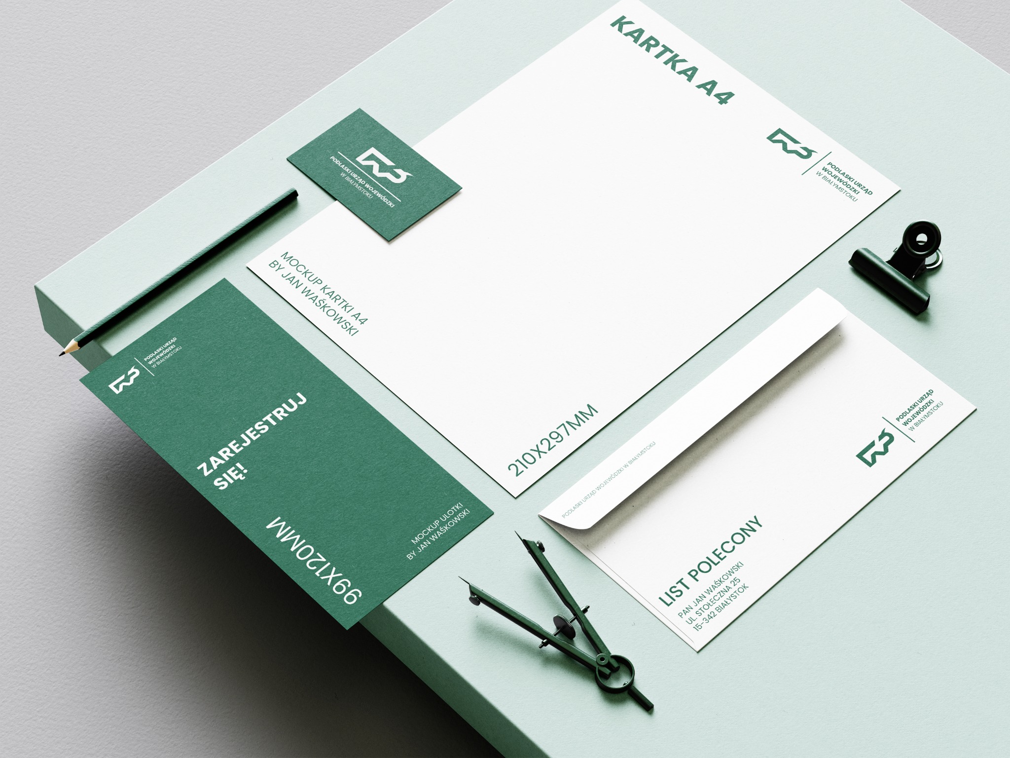 Zestaw materiałów biurowych w odcieniach zieleni: wizytówka, ulotka, koperta, kartka A4 z logo Podlaskiego Urzędu Wojewódzkiego, ołówek i cyrkiel.