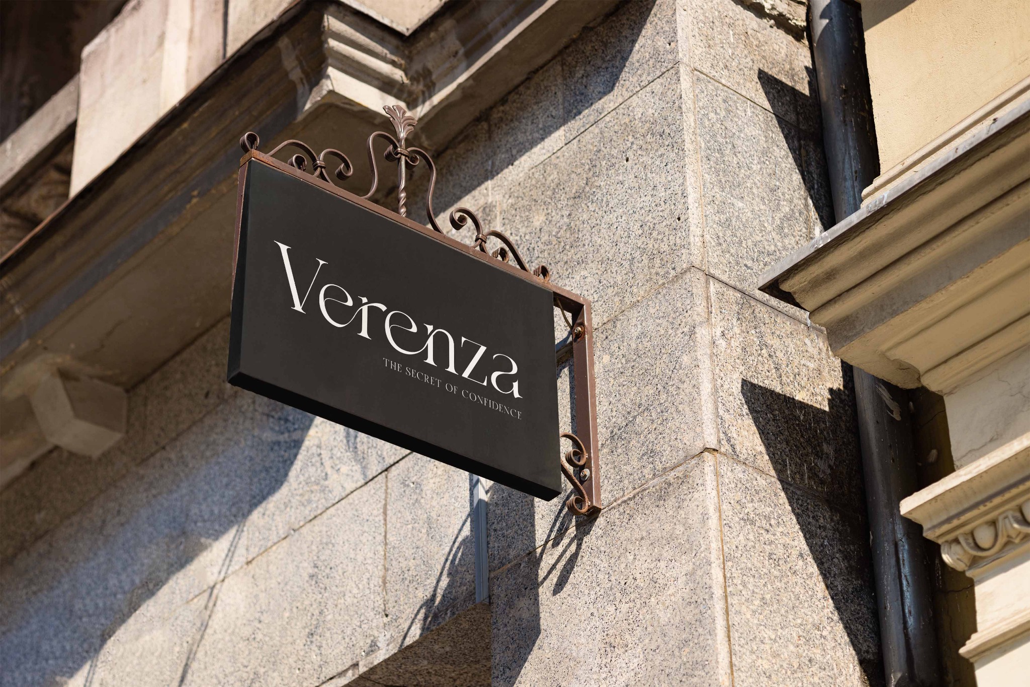 Elegancki, czarny szyld z nazwą 'Verenza' i hasłem 'The secret of confidence' zawieszony na ozdobnym, metalowym wsporniku na tle kamiennej fasady budynku.