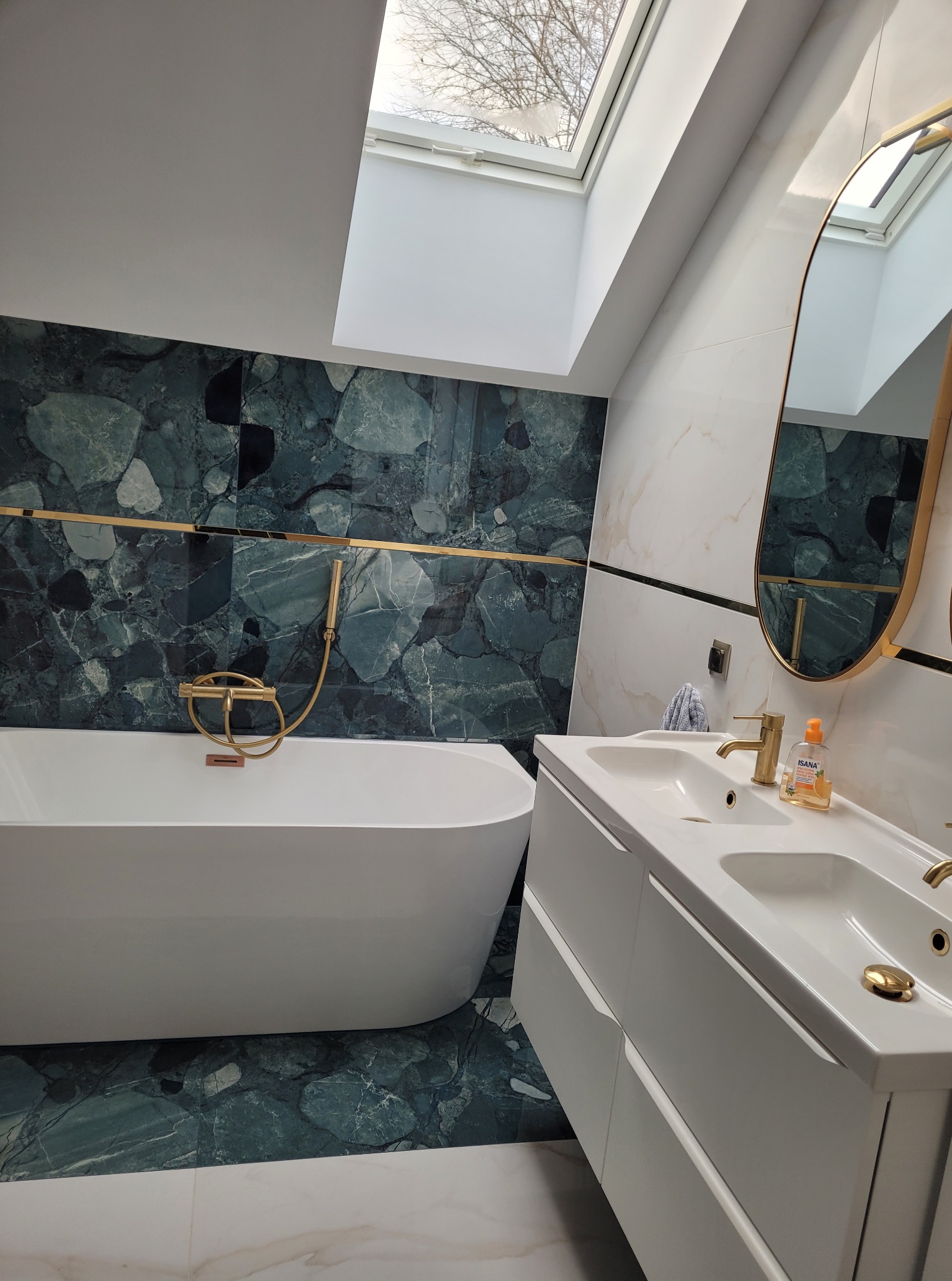 Nowoczesna łazienka z wanną wolnostojącą, umywalką nablatową i marmurowymi płytkami w odcieniach zieleni i bieli, doświetlona oknem dachowym.