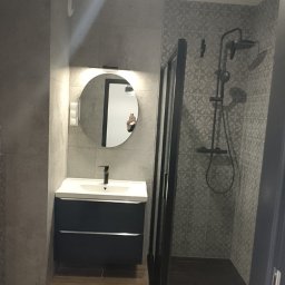 Mar-Motomax Reaktywacja Mariusz Pewniak - Nowoczesna łazienka z kabiną prysznicową typu walk-in, okrągłym lustrem z podświetleniem i szafką pod umywalką w kolorze granatowym. Minimalistyczny design.