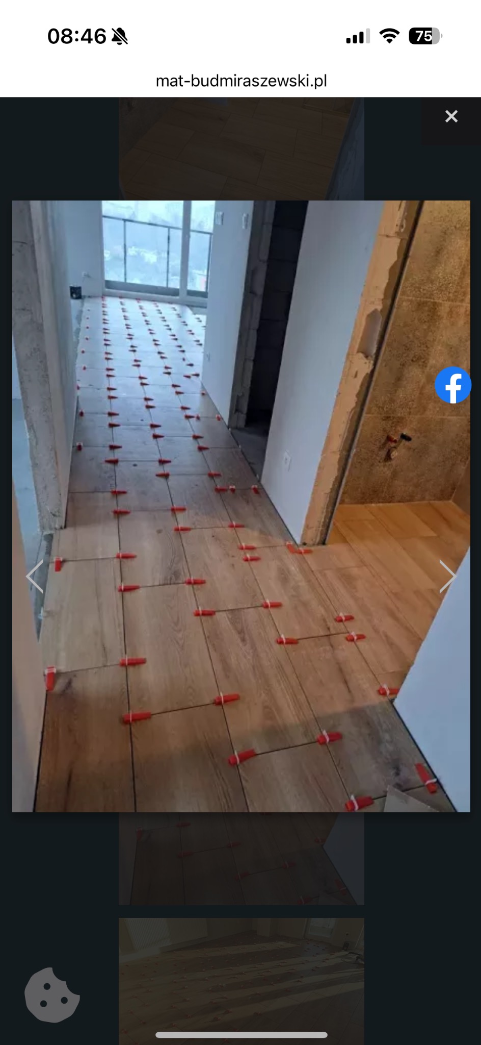 Układanie drewnopodobnych płytek w korytarzu z użyciem czerwonych krzyżyków dystansowych. Widoczne fragmenty okna i drzwi. Etap prac wykończeniowych.