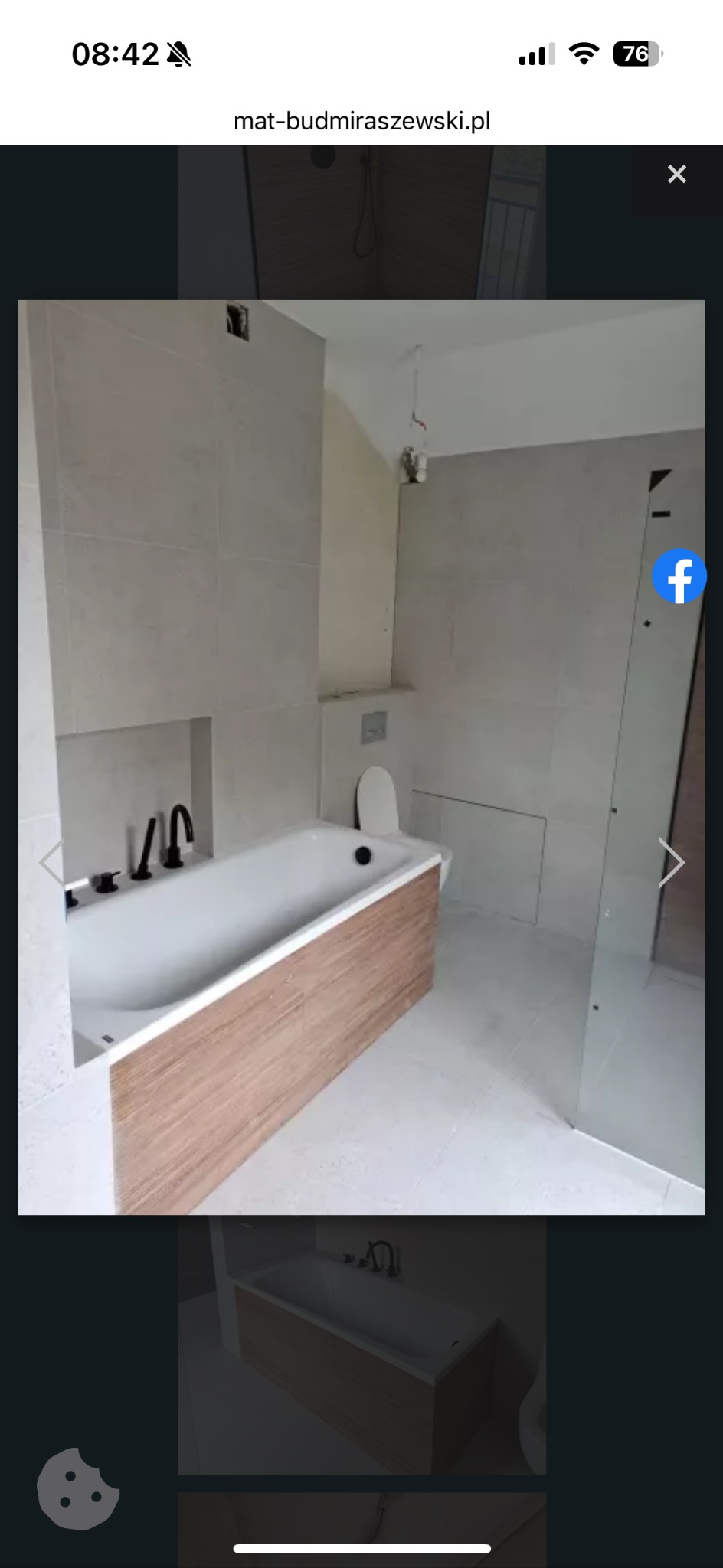 Wykończona łazienka z wanną obudowaną drewnem, szare płytki, czarna armatura i szklana kabina prysznicowa. Minimalistyczny design.